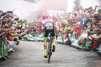 View of the back of Mike Woods riding between barriers and crowds towards the finish during his stage win in La Vuelta 2018.