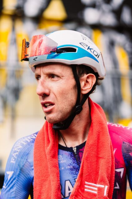 Photo of Mike Woods post race with a towel around his neck and mud splattered on his glasses